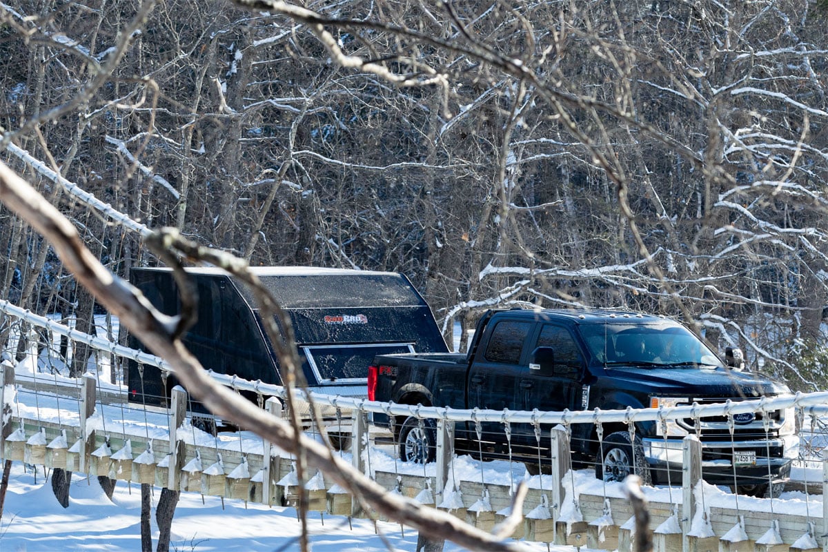 Black Truck Hauling Black Hybrid SnoPro Trailer Through Snow