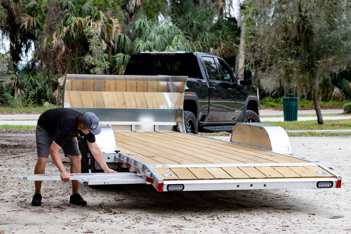 Person Putting Away Ramps In Open Wood Deck Car Hauler