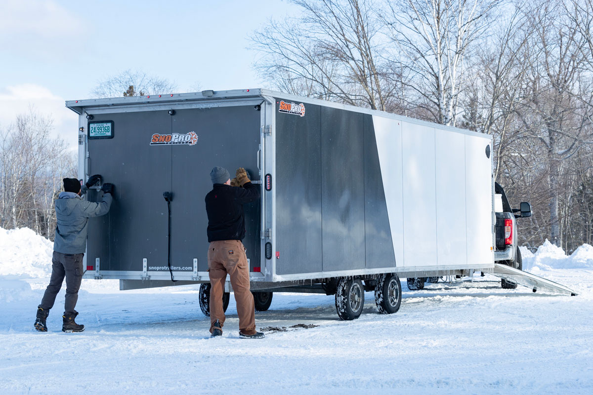 Two Men Opening Rear Ramp On SnoPro Enclosed Deckover 6.5-Height Snow Trailers Two Men Opening Rear Ramp On SnoPro Enclosed Deckover 6.5-Height Snow Trailers